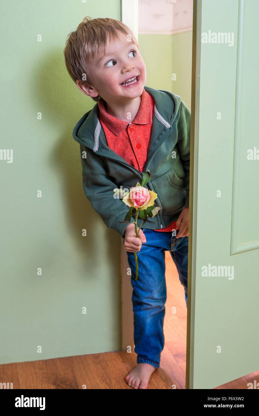 Fröhliche kleine Junge hält eine rose Stockfoto