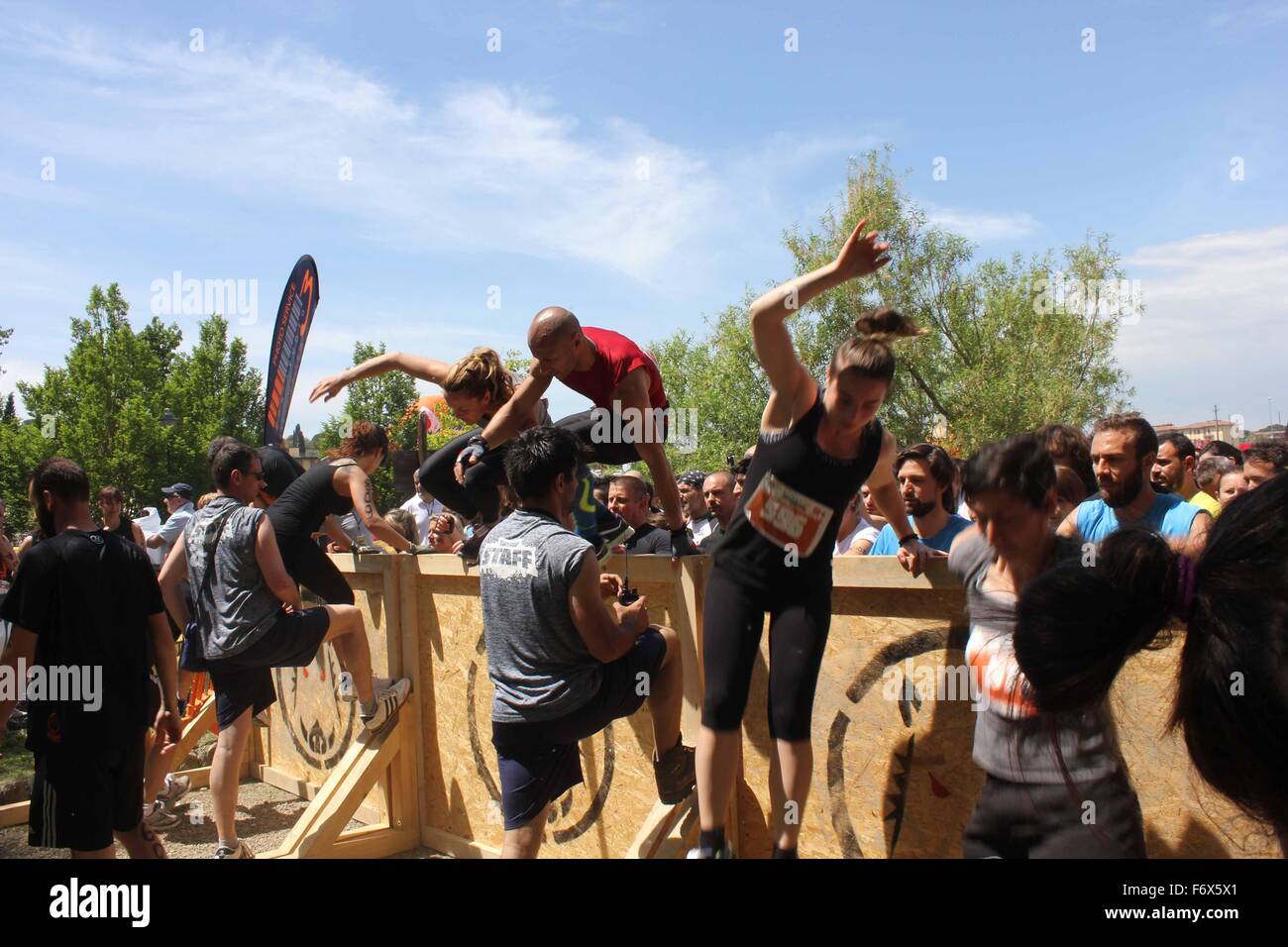 SIGNA, Italien - 9. Mai 2015: Gruppe von Menschen, die einen Sprung über ein Hindernis während der Inferno laufen Schlamm Rennen in Florenz Stockfoto