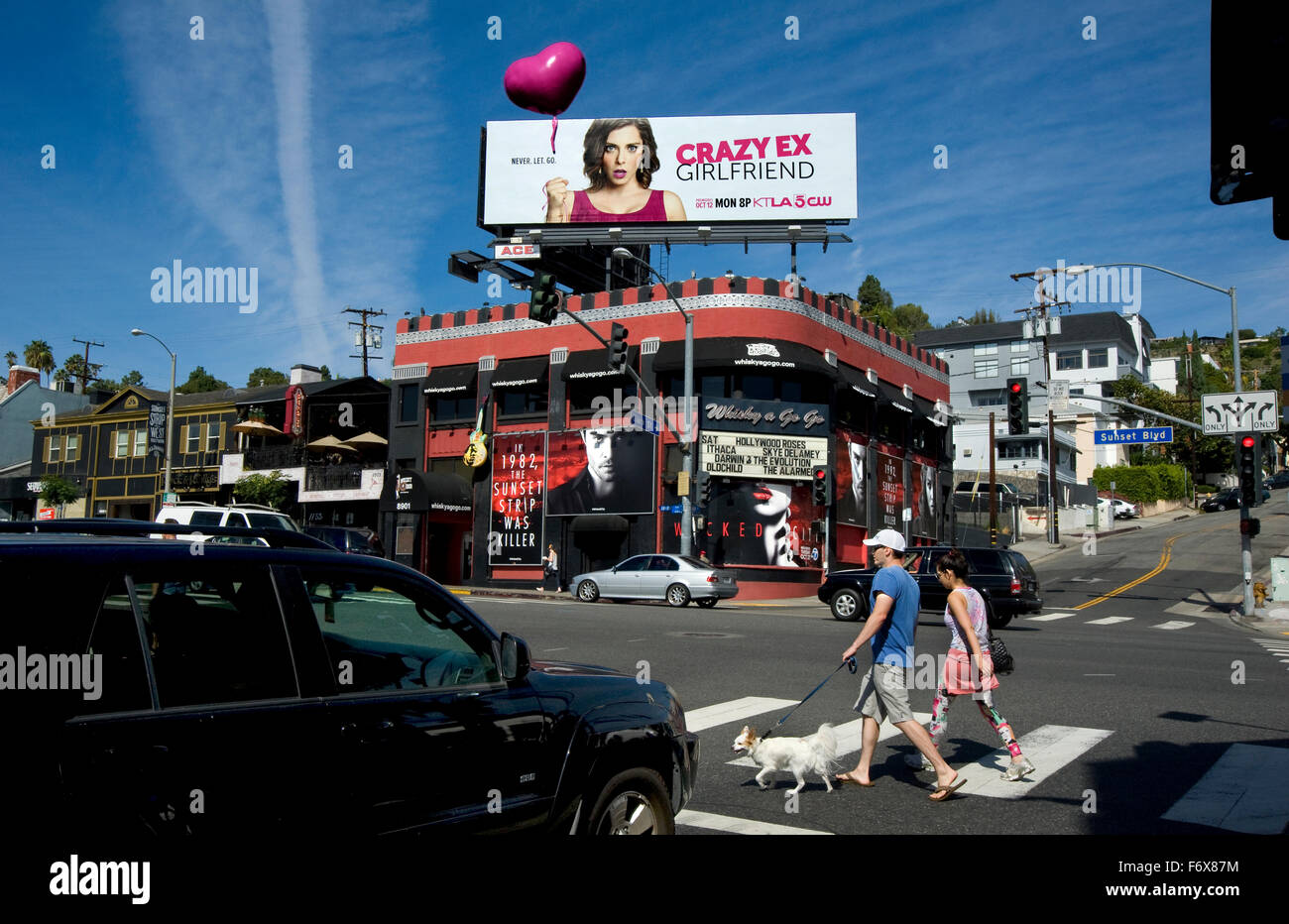 Paare, die auf dem Sunset Strip in der Nähe des Whisky A Go Go Nachtclub mit einer bunten Plakatwand in West Hollywood. Stockfoto