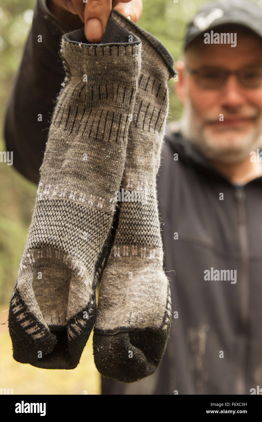 Mann hält seine stinkenden Socken nach einer zweiwöchigen Kanutour auf dem Wind River; Yukon, Kanada Stockfoto