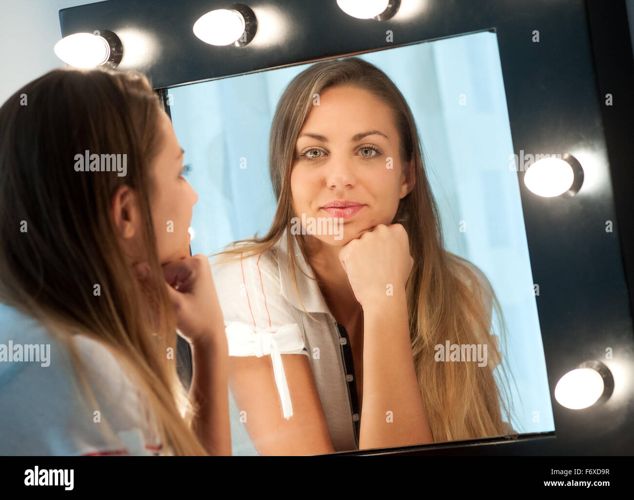 Attraktive junge Mädchen mit langen braunen Haaren sitzen an einer Frisierkommode starrte in den Spiegel Stockfoto