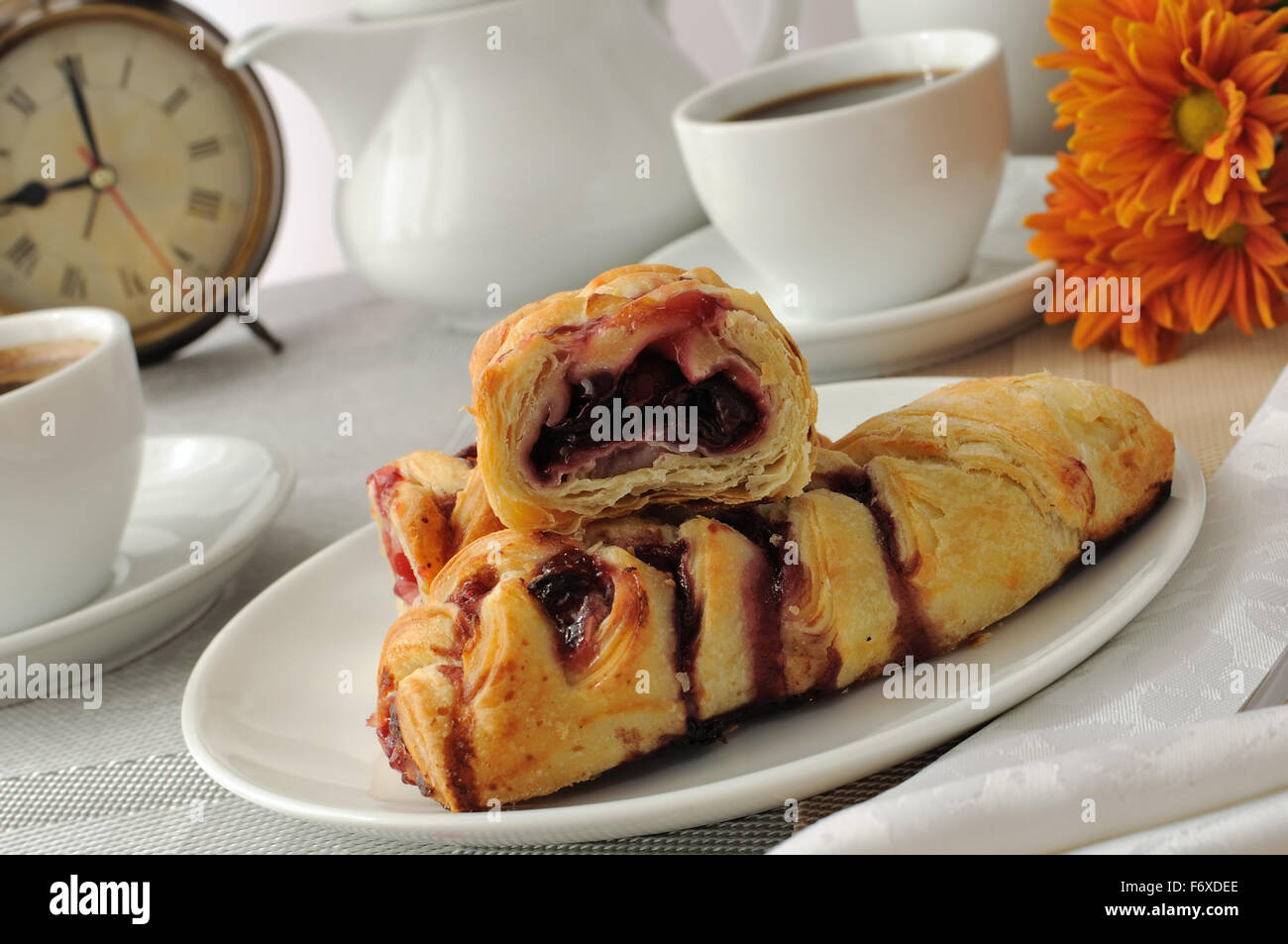 Ein Stück Strudel mit Kirschen mit einer Tasse Kaffee am Morgen Stockfoto