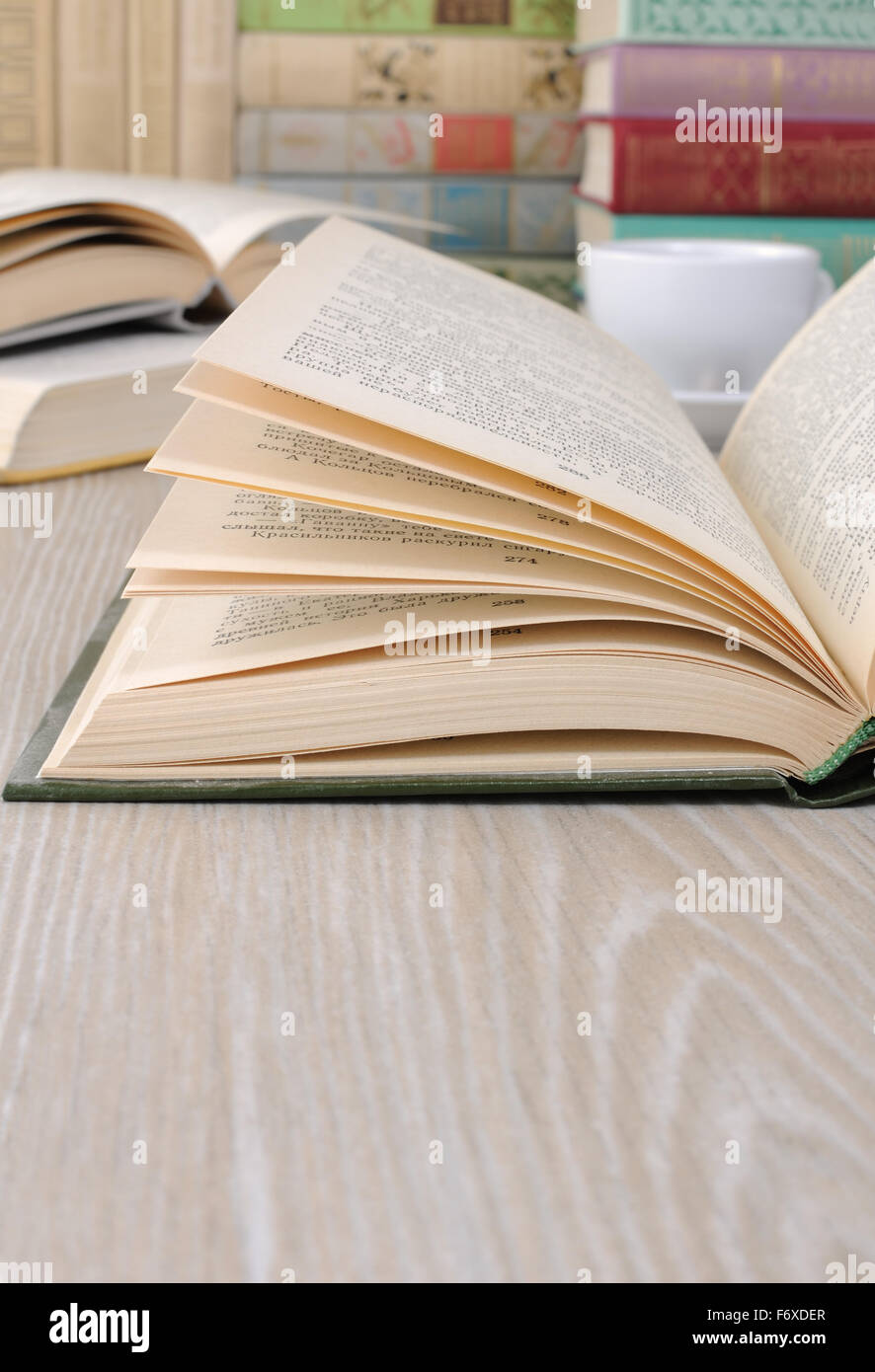 Ein Fragment eines aufgeschlagenen Buches auf dem Tisch unter anderen Büchern Stockfoto
