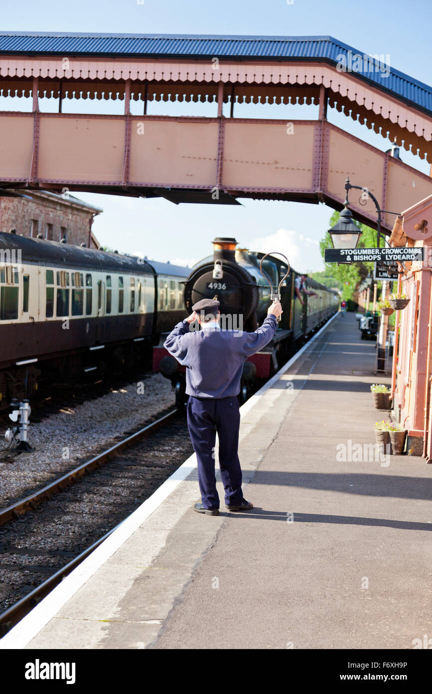 Der Stellwerkswärter tauscht einen einzeilige Token mit der Feuerwehrmann der Dampfzug an Williton Station auf der West Somerset Railway, En Stockfoto
