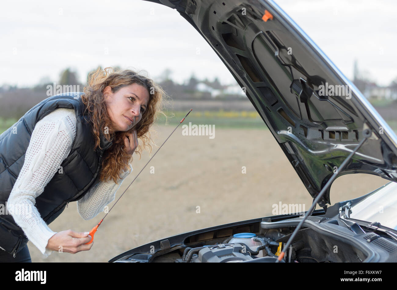 Frau Auto eine Panne hat und sie prüft den Ölstand Stockfoto