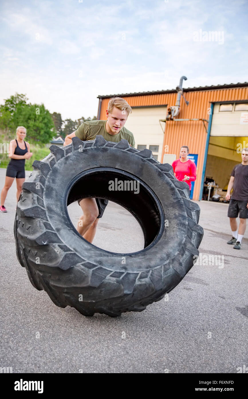 Starker Mann kippt schwere Reifen im Freien Training Stockfoto