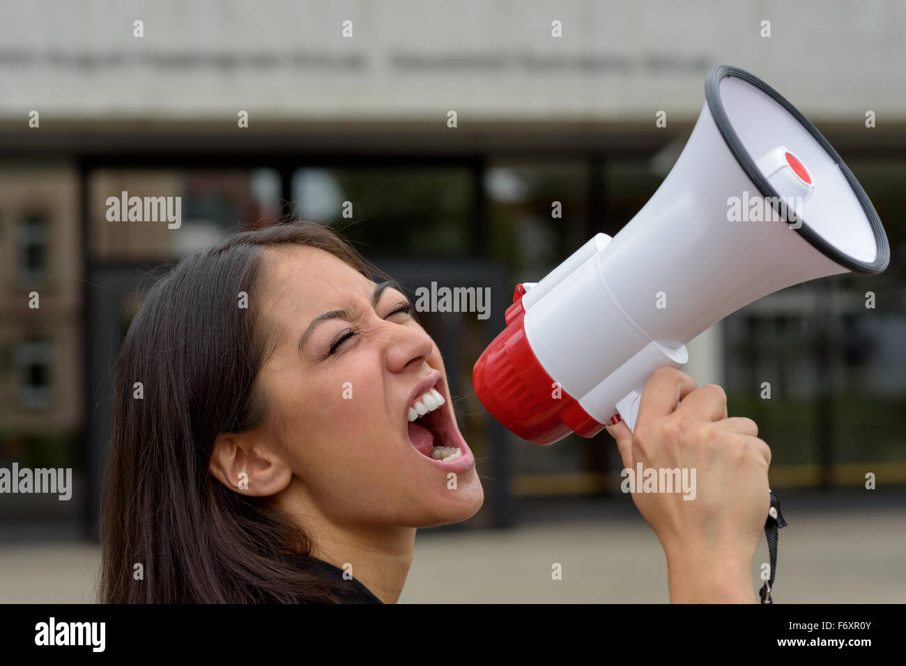 Böse junge Frau, die über ein Megaphon oder Megaphon schreien, wie sie in einer Straßendemonstration oder Protest lüften ihre Entdekung teilnimmt Stockfoto