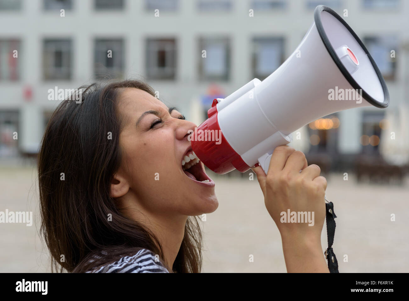 Frau schreien in ein Megaphon auf einer städtischen Straße äußern ihre Displaeasure bei einem Protest oder Vorführung, Nahaufnahme Seitenansicht Stockfoto