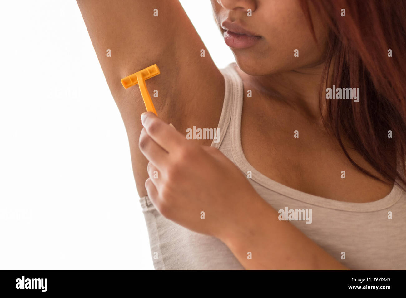 Nahaufnahme junge Afro-amerikanische Frau rasieren ihr Unterarm verwenden eine manuelle Rasierer gegen weißer Hintergrund. Stockfoto