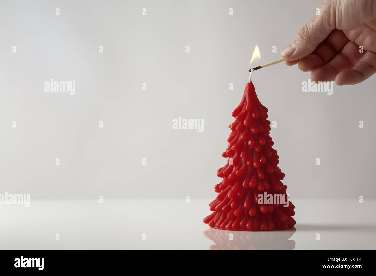 Mans Hand hält ein Match, das Anzünden einer Kerze in der Form eines Weihnachtsbaumes Stockfoto