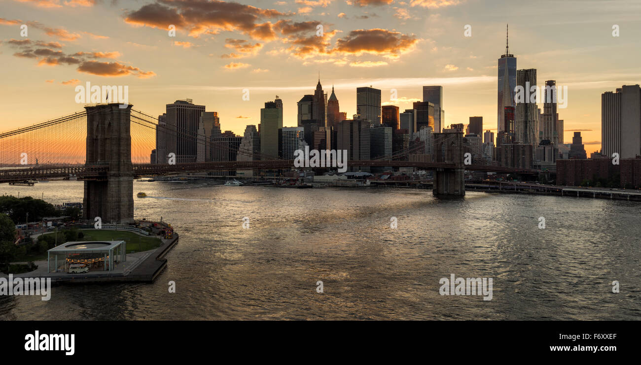 Lower Manhattan Wolkenkratzer und Financial District Skyline bei Sonnenuntergang mit der Brooklyn Bridge über den East River, New York CIty Stockfoto