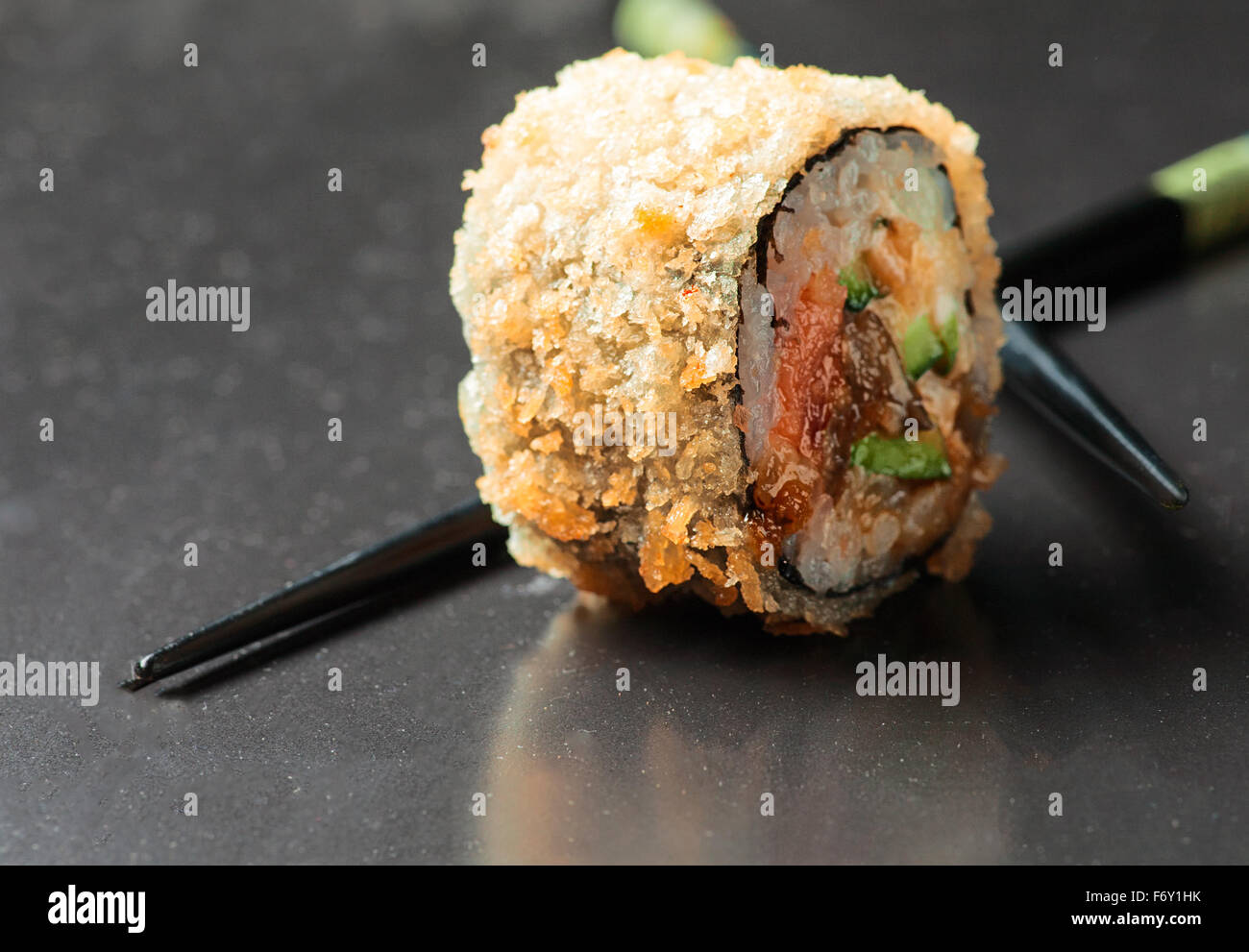 Makroaufnahme einer heißen Sushi mit Stäbchen auf schwarz mit unscharfen Reflexion Stockfoto