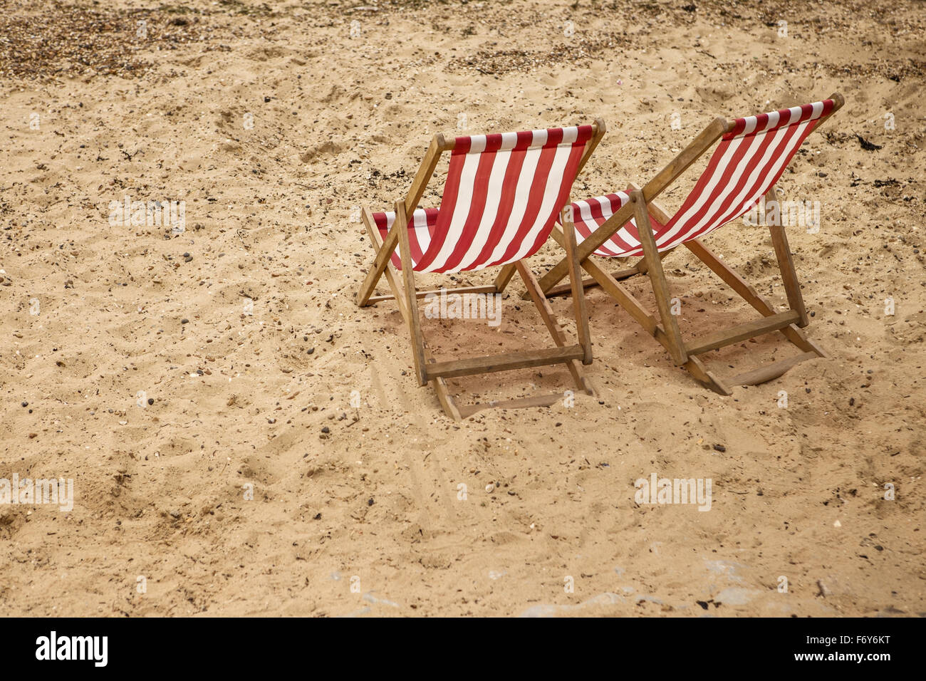 zwei Liegestühle von ihnen selbst stehend auf einem Sandstrand Stockfoto