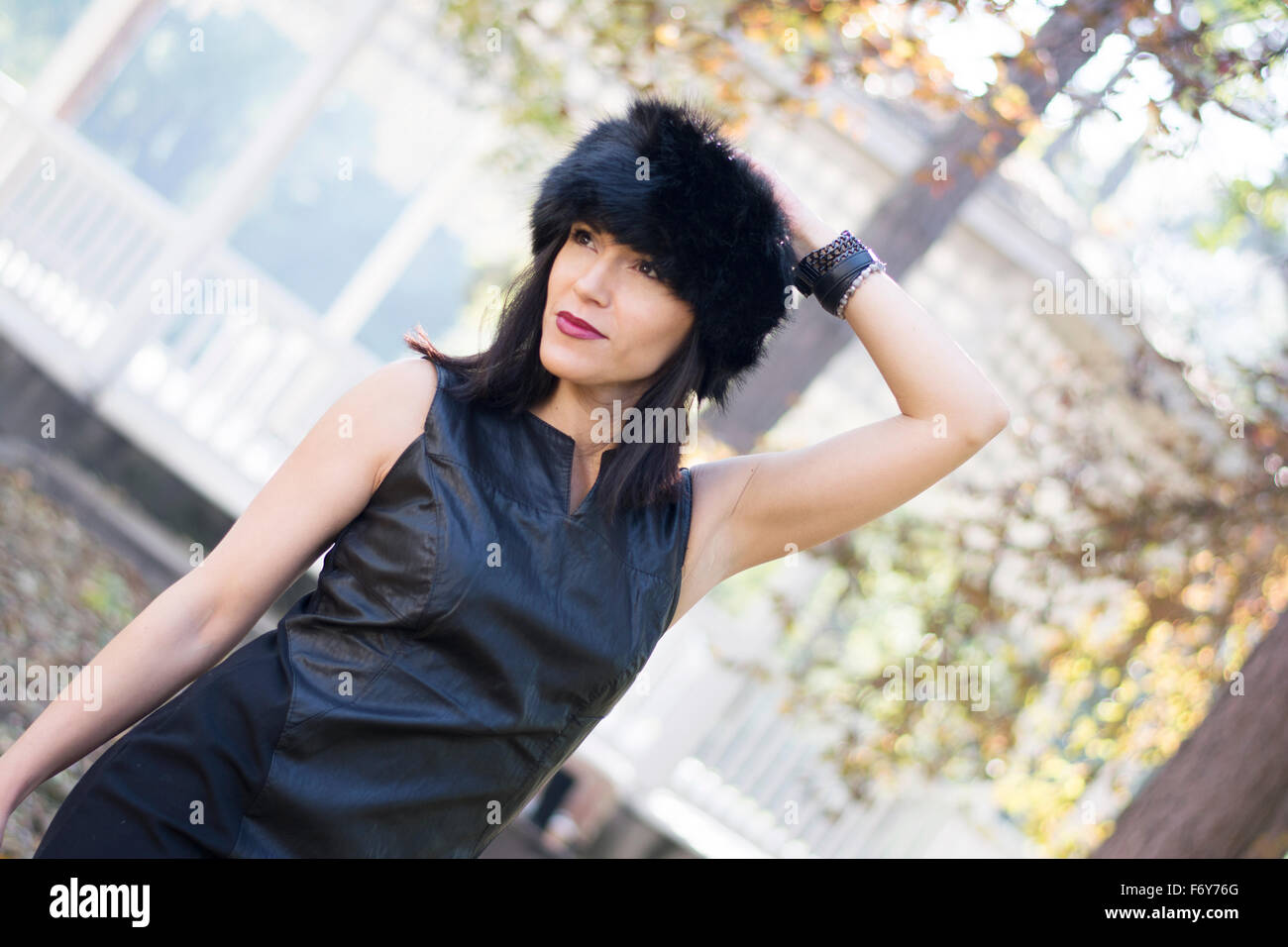 Schöne und attraktive schwarze dunkelhaarige Frau posiert für ein Mode-Shooting im Park im Herbst Stockfoto