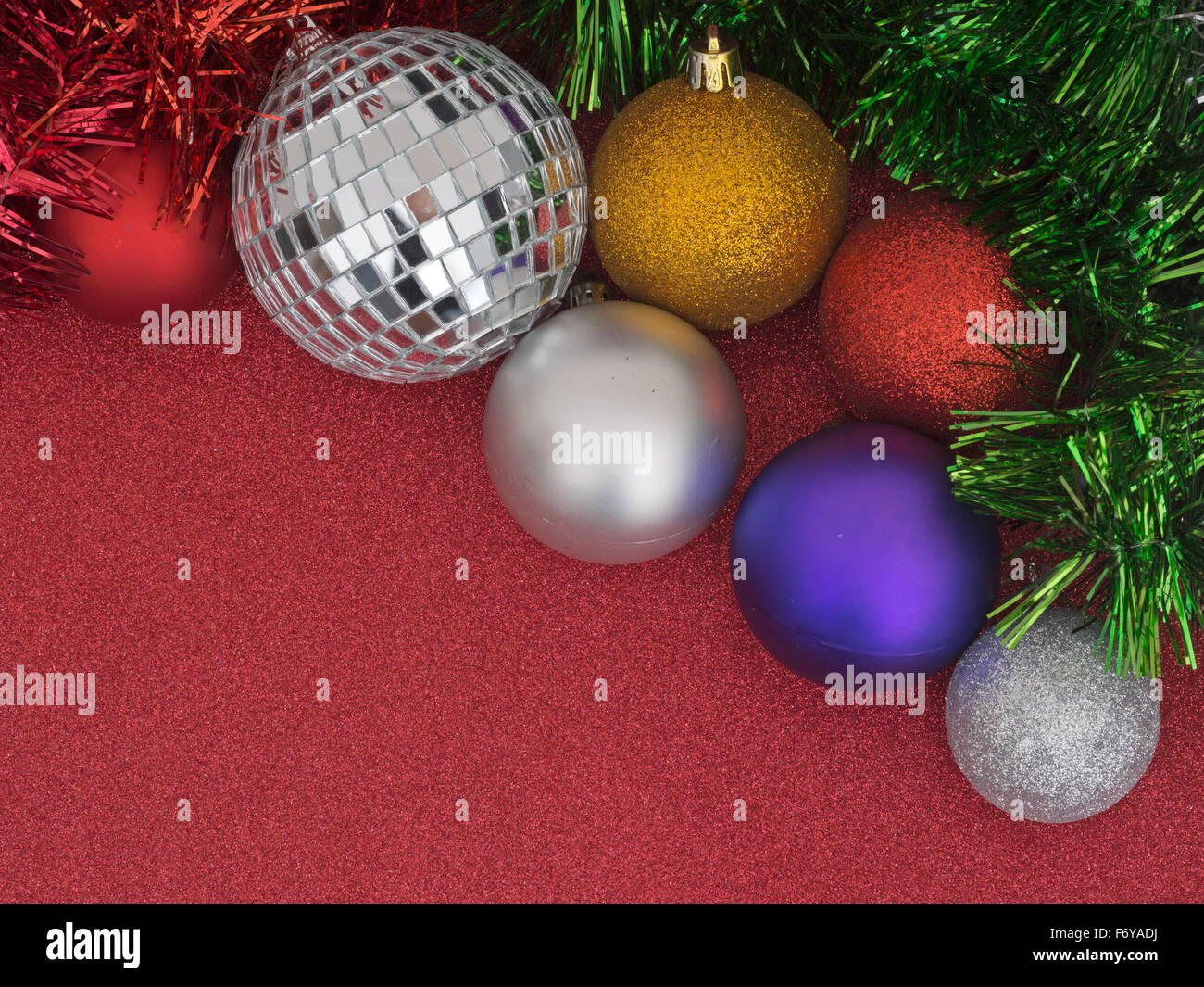 Weihnachtsvorbereitungen, Hintergrund. Kugeln und Lametta auf glitzernde rote. Stockfoto