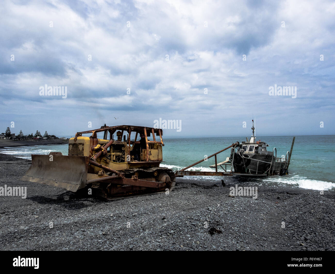 Allis Chalmers Bulldozer schleppen Fischerboot aus dem Ozean, Ngawai, Palliser Bay, Wairarapa, Neuseeland Stockfoto