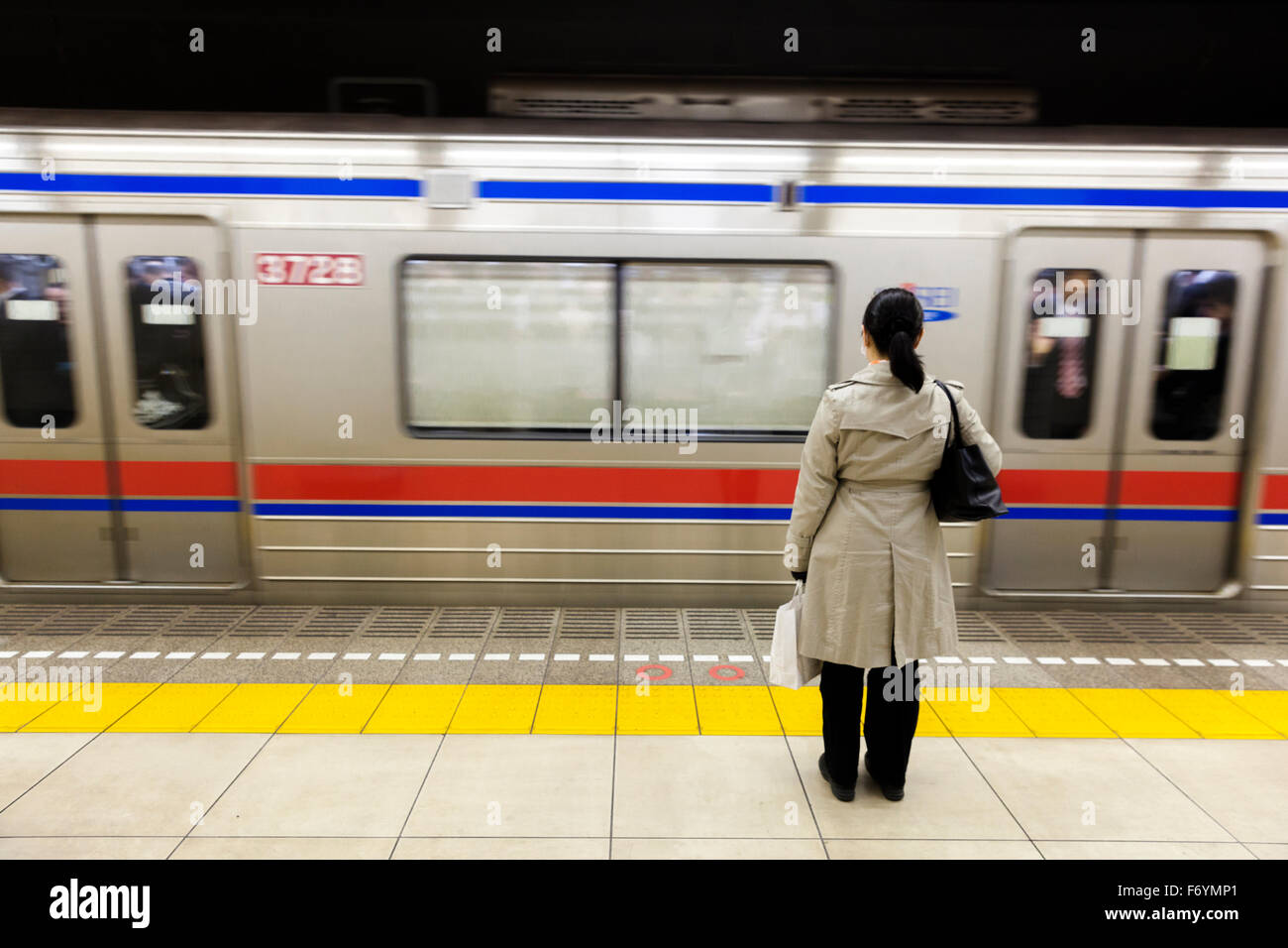 Eine japanische Frau wartet im Untergrund für einen vorbeifahrenden Zug Stockfoto
