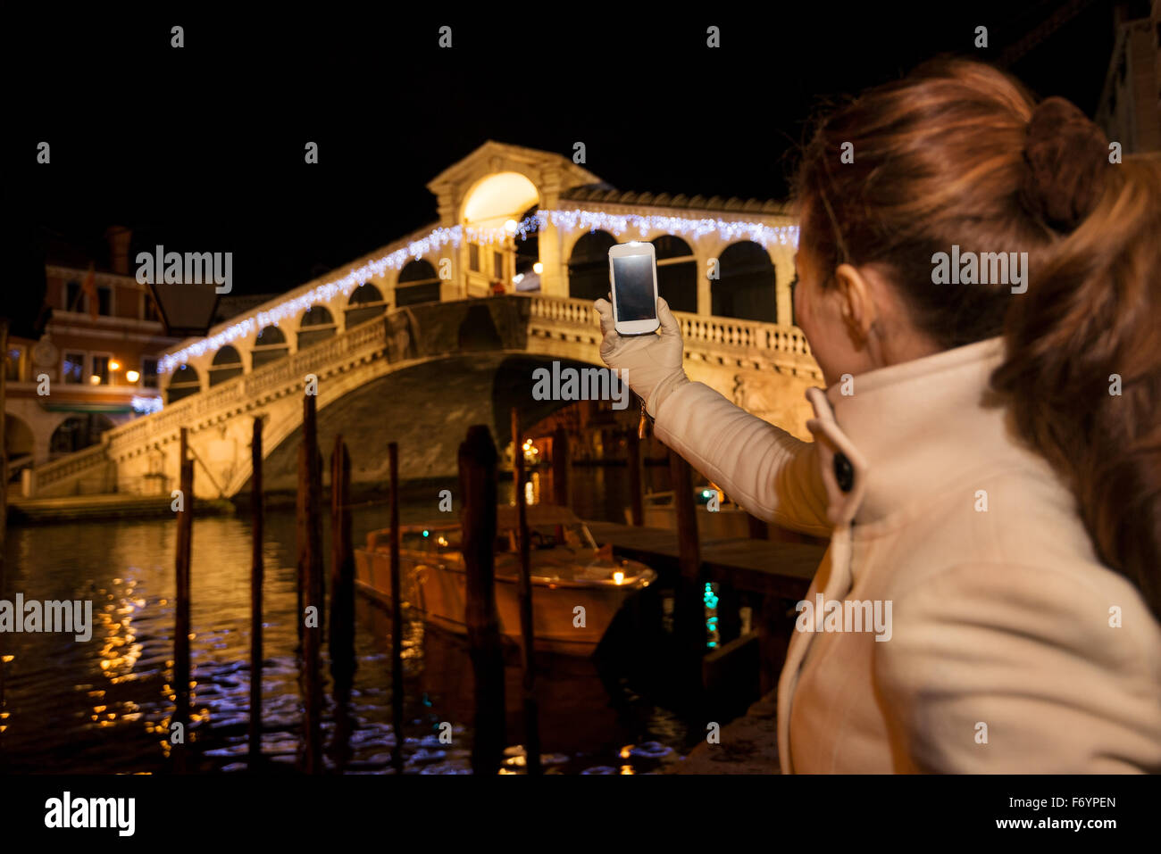 Gesehen von hinten, elegante Frau im weißen Kittel Foto vor Rialto-Brücke steht am Abend. Sie haben C Stockfoto