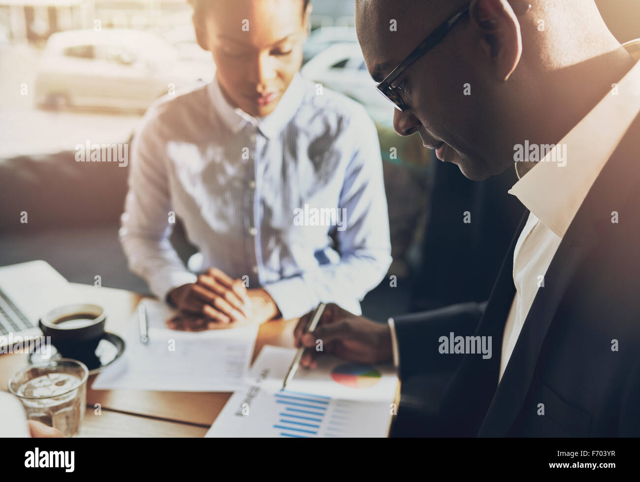 Zwei schwarze Geschäftsleute über ihre Geschäfte mithilfe von Diagrammen, um ihren Erfolg zu beweisen Stockfoto