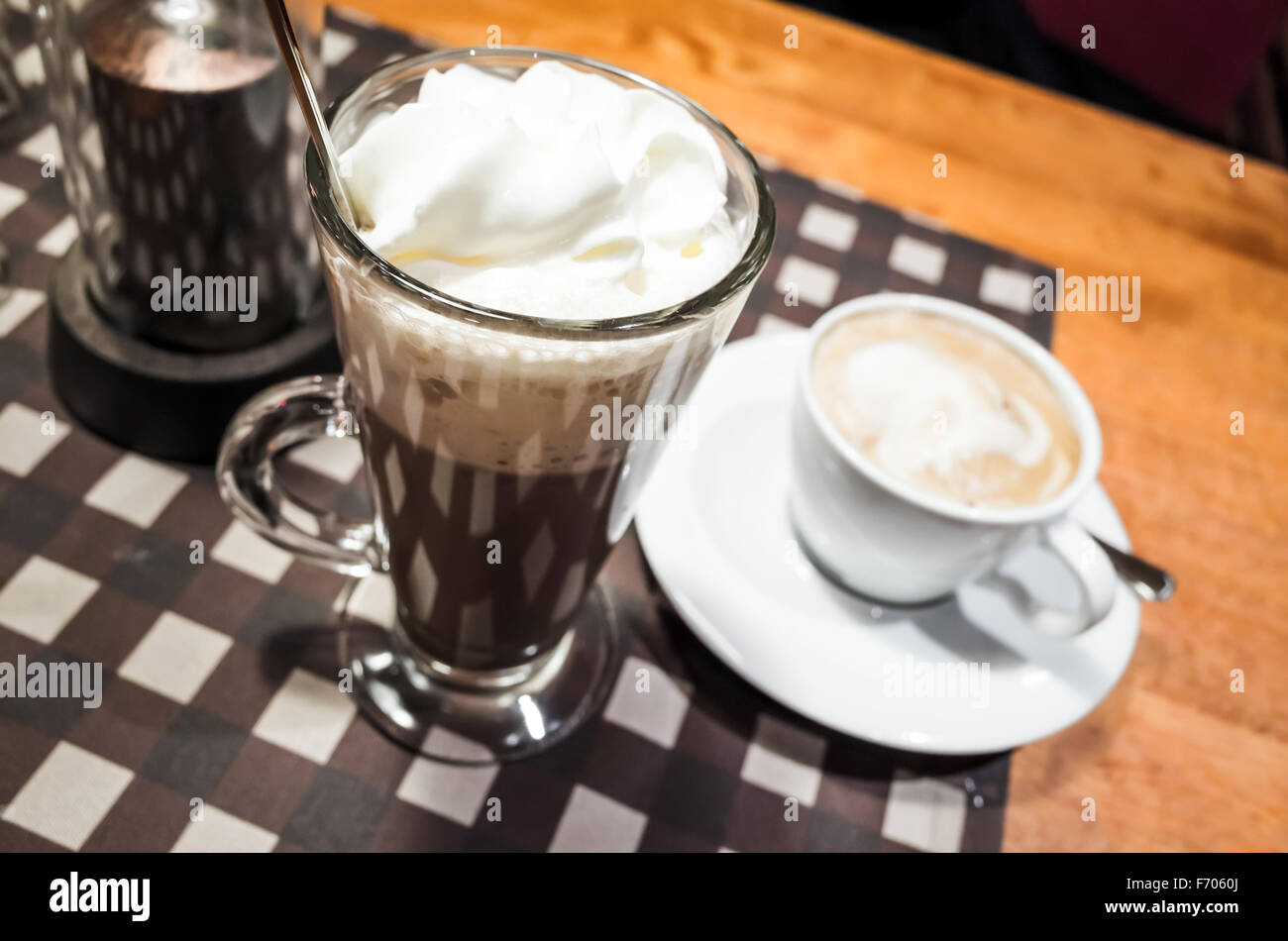 Glas heiße Schokolade und weißen Tasse Cappuccino Kaffee stehen auf einem Tisch Stockfoto