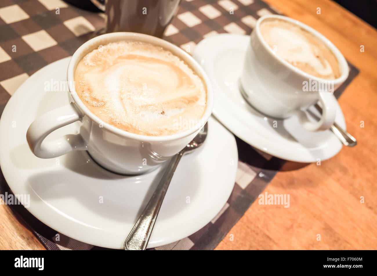 Weiße Tassen Cappuccino voller stehen auf Holztisch, Retro-Stil Tonwertkorrektur Foto filtern und selektiven Fokus Stockfoto