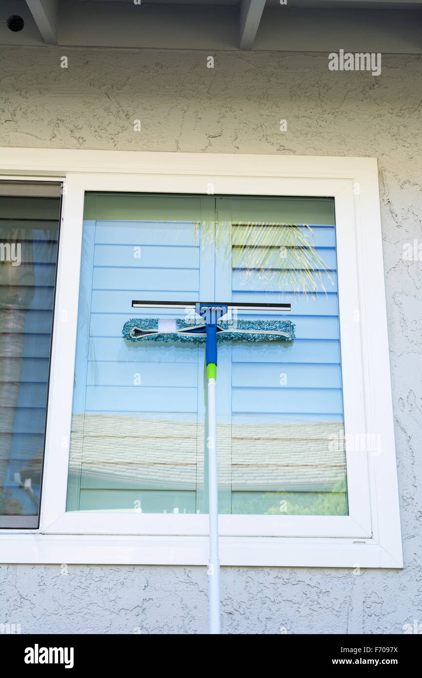Fensterputzer verwendet einen Schwamm und ein Rakel auf einem Pfahl der Außenfenster von zu Hause zu waschen. Stockfoto