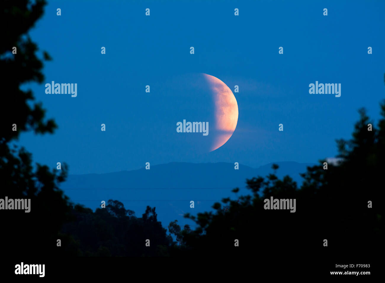 Der Mond steigt während einer seltenen Sonnenfinsternis, die von der Dämmerung zur Dunkelheit am Abend Stockfoto