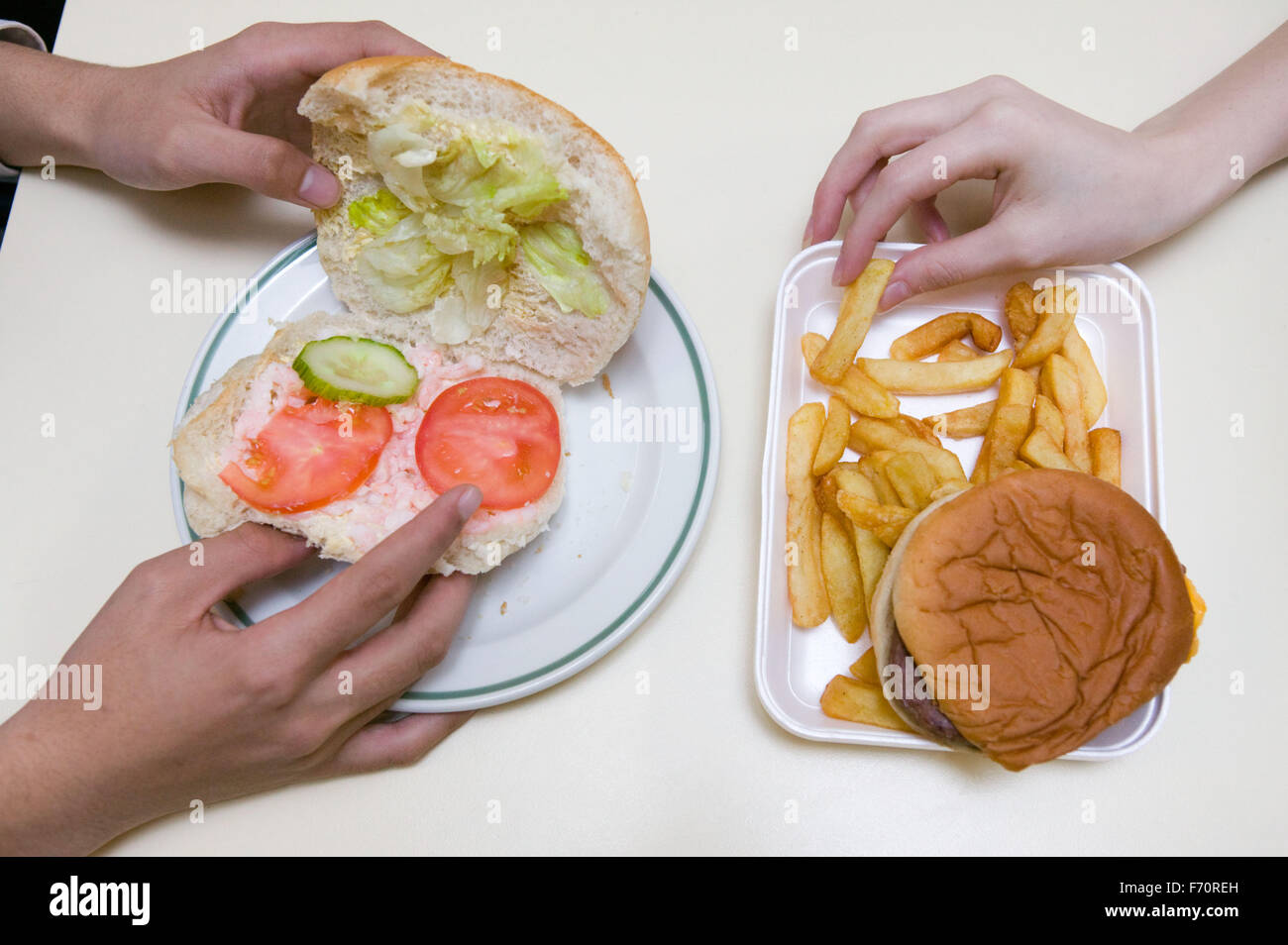 Schulspeisung von Garnelen und Salat Roll oder einen Karton mit Burger und Pommes frites; Richtlinien der Regierung fördern Schulen weniger He ersetzen Stockfoto