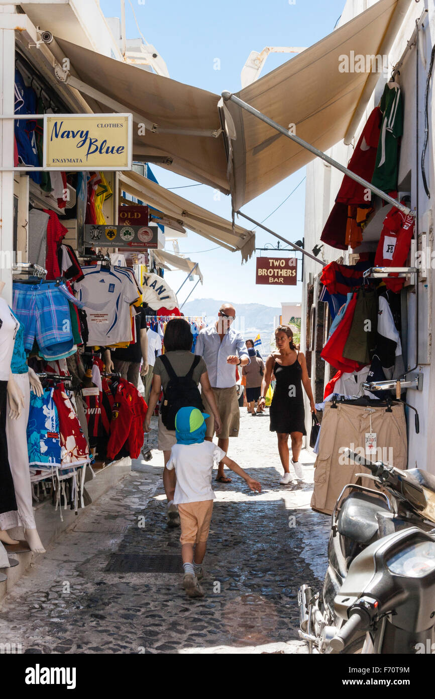 Santorini. Touristen zu Fuß durch die typischen engen gepflasterten Straße mit Geschäften auf beiden Seiten und Markisen Overhead, im alten Stadtzentrum von Fira entfernt. Stockfoto