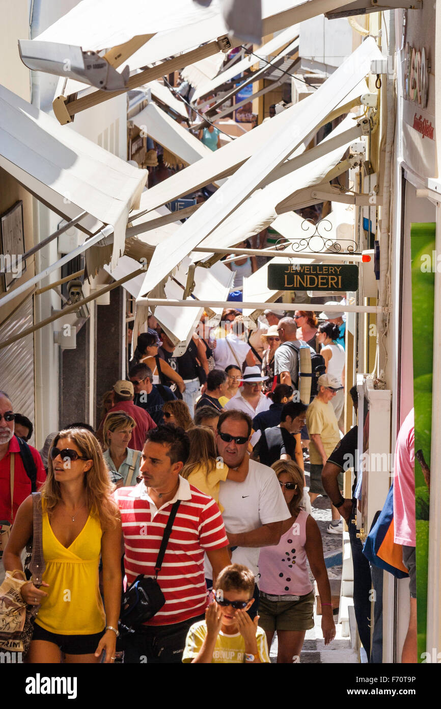 Santorini. Touristen zu Fuß durch die typischen engen gepflasterten Straße mit Geschäften auf beiden Seiten und Markisen Overhead, im alten Stadtzentrum von Fira entfernt. Stockfoto