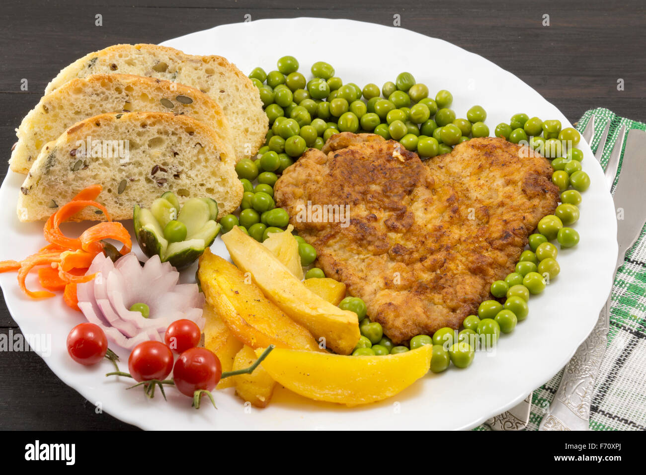 Steak mit Kartoffeln, Tomaten und grüne Bohnen auf einem Teller in Herzform Stockfoto