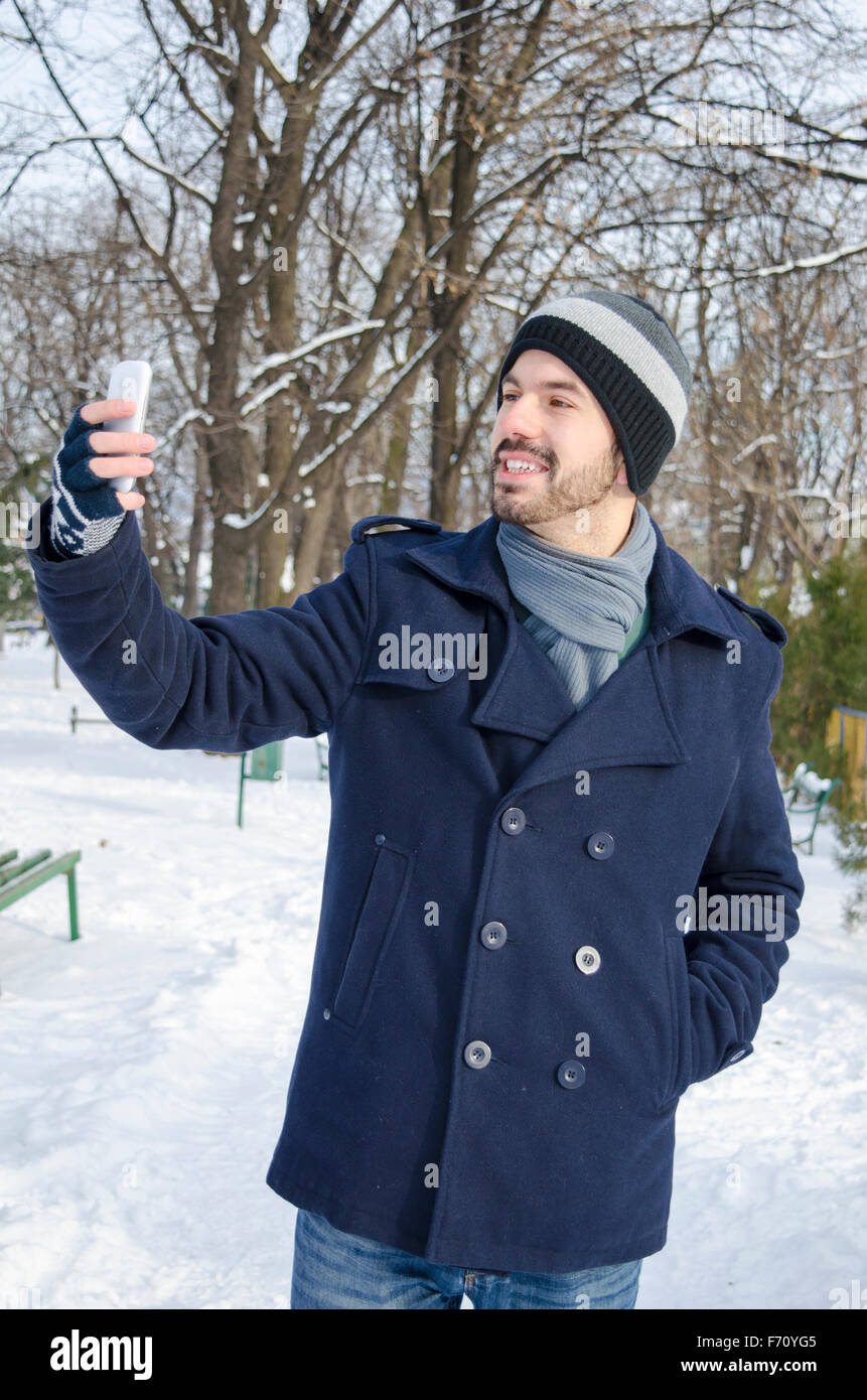 Junge bärtigen Mann, der ein Selbstporträt in einem Park an einem sonnigen Wintertag Stockfoto