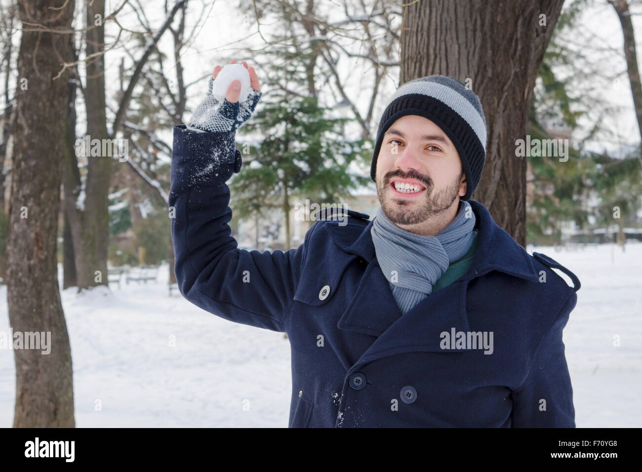 Junger Mann warf einen Schneeball in einem verschneiten park Stockfoto
