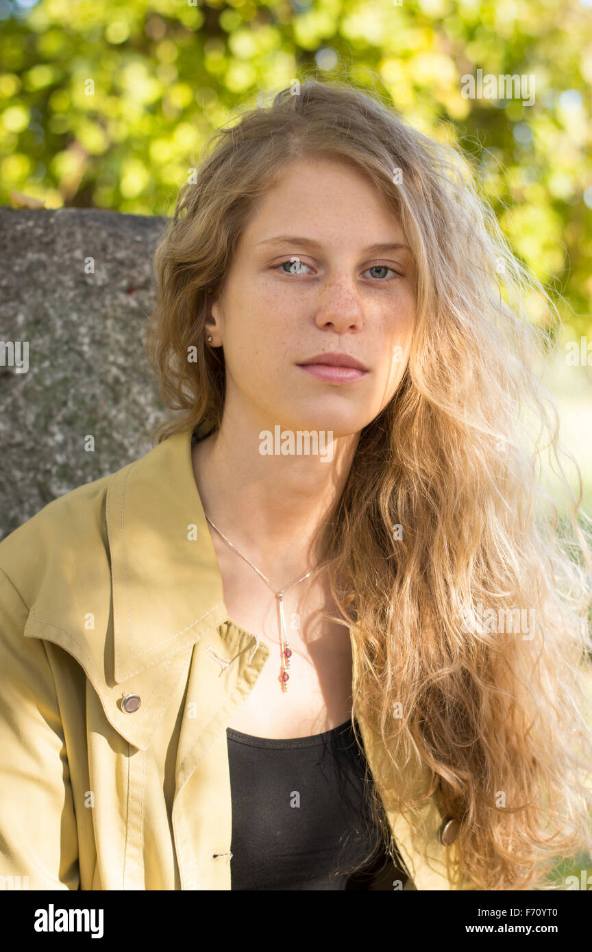 Porträt von einem schönen blonden Mädchen sitzt in einem park Stockfoto