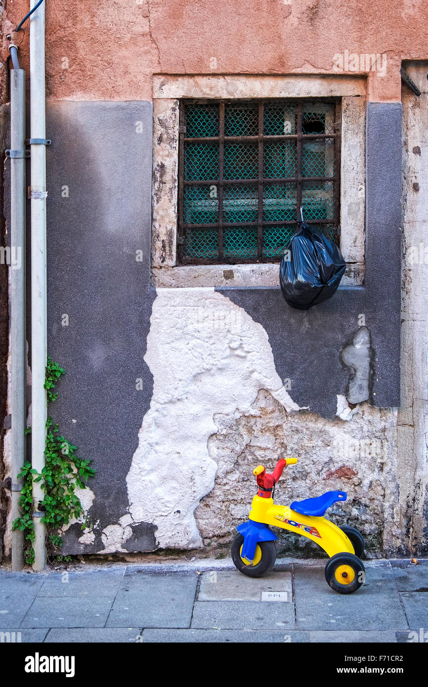 Venedig, Castello. Typischen venezianischen Haus außen mit Wasser beschädigt, Wand, Fenster, des Kindes Dreirad Stockfoto
