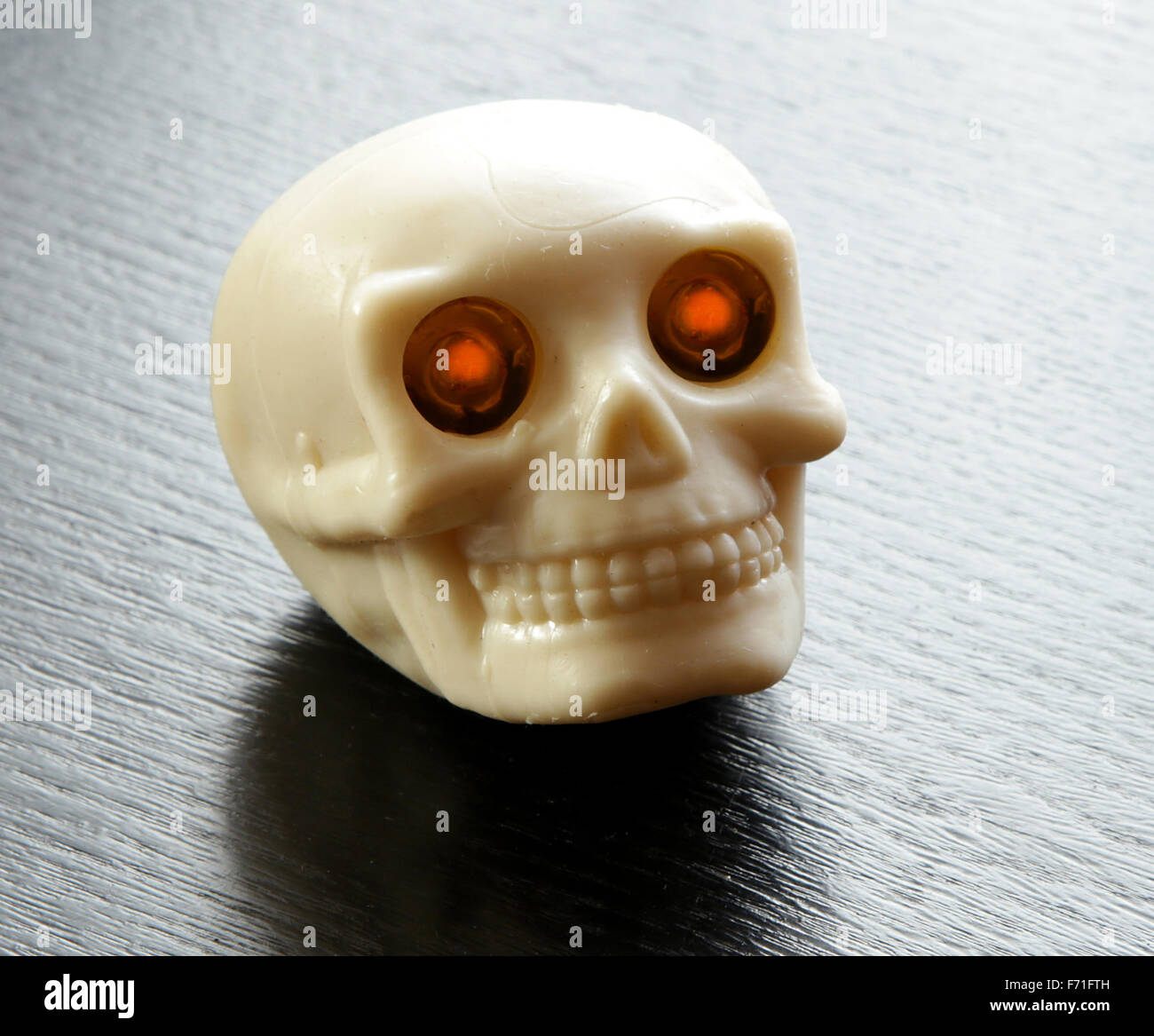 Vintage menschlicher Schädel mit beleuchteten Augenbrennen am schwarzen Tisch Stockfoto