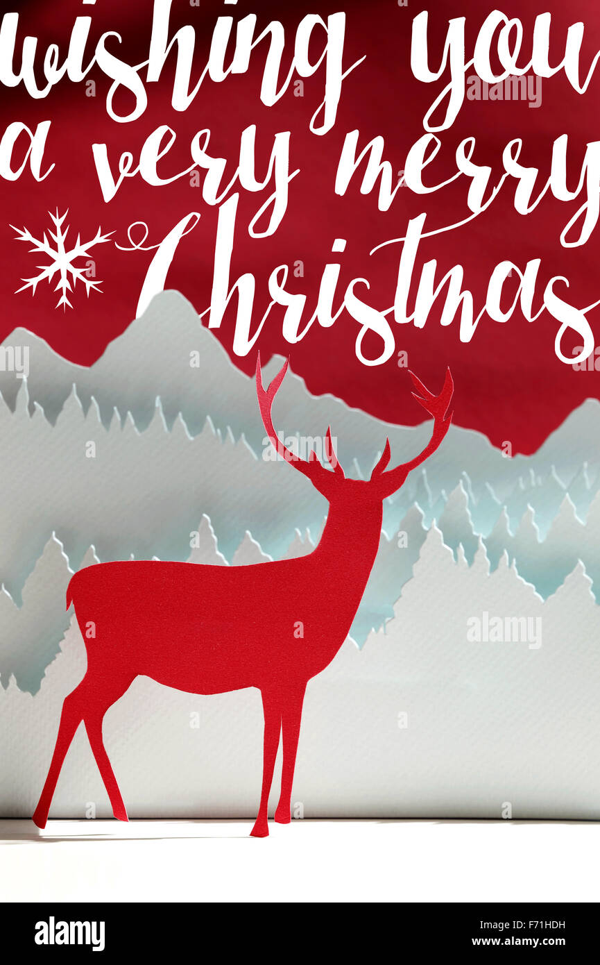 Frohe Weihnachten handgeschöpftes Papier geschnitten Kunst-Winter-Szene: Rothirsch Papercraft mit Schnee Waldlandschaft auf Texthintergrund. Stockfoto