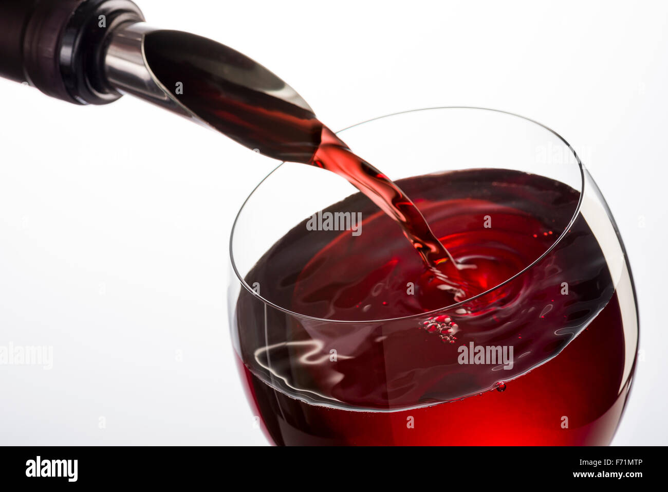 Flasche mit Tülle Gießen Rotwein in Glas auf weißem Hintergrund Stockfoto
