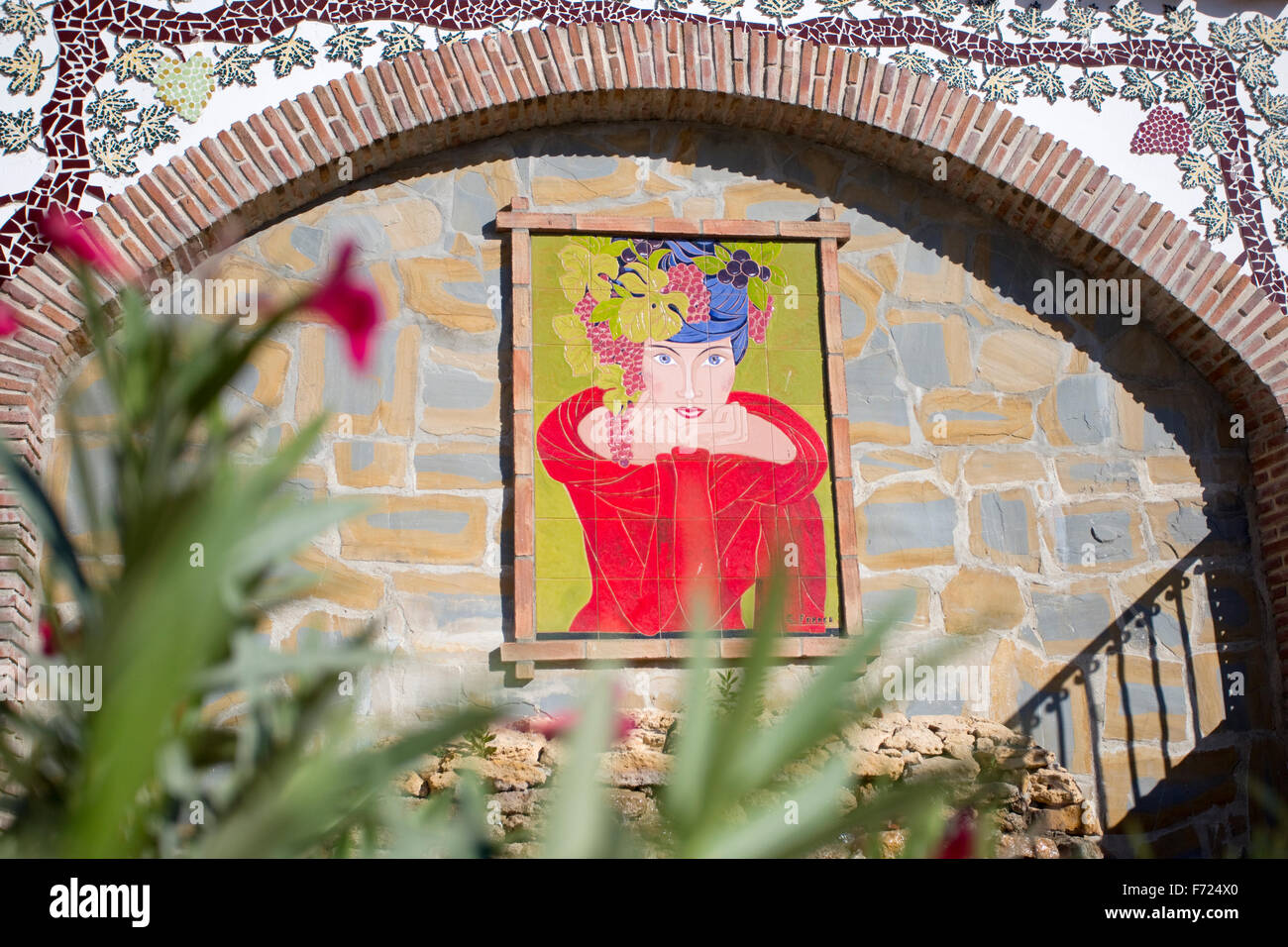 Ein Bild von einer Frau im roten Kleid gegen eine Wand in der Straße im Dorf von Manilva, Andalusien, Spanien. Stockfoto