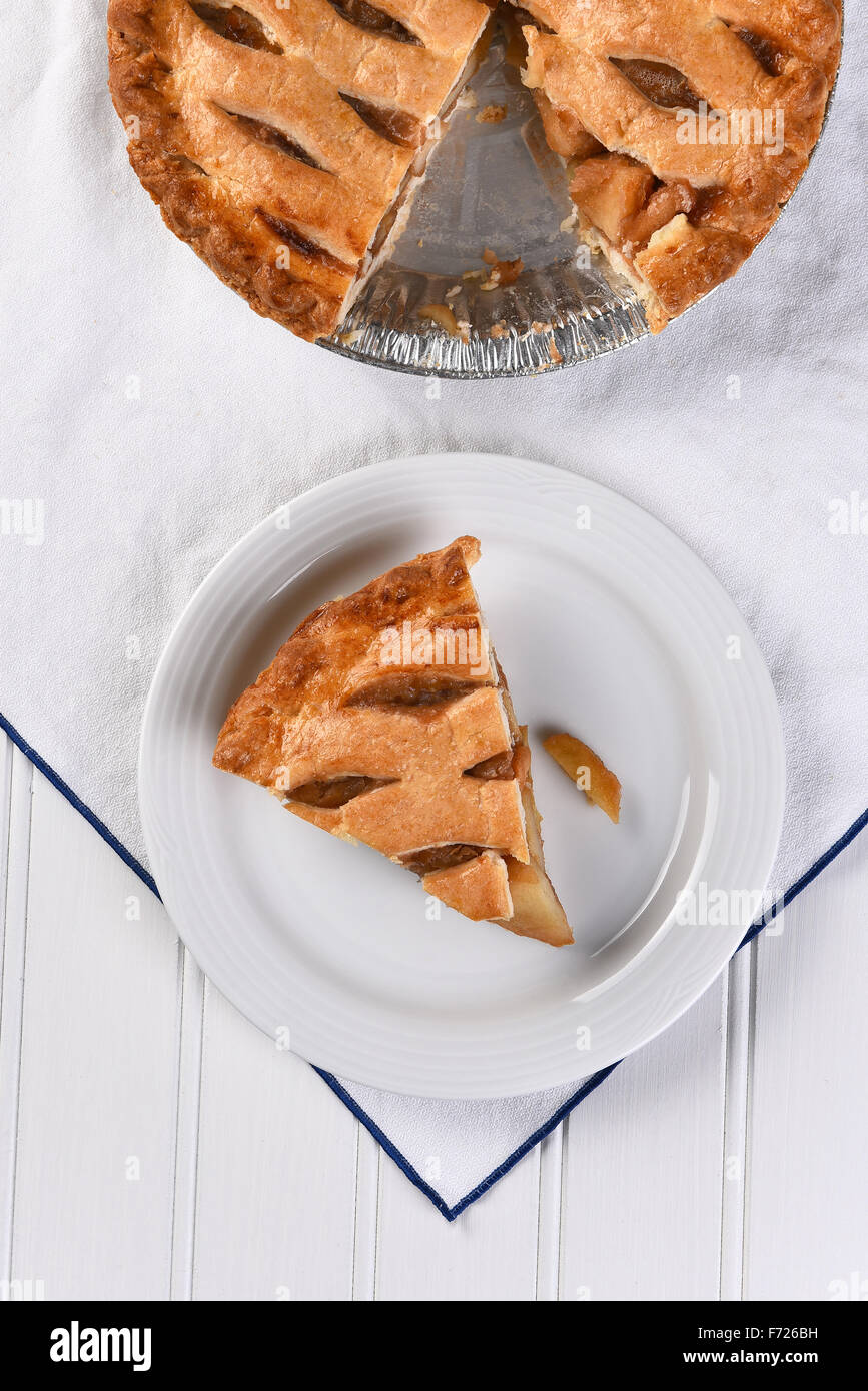 Draufsicht auf ein Stück Apfelkuchen auf einem Teller den Rest des Diagramms ist an der Oberseite des Rahmens. Hochformat auf weißen Handtuch Stockfoto