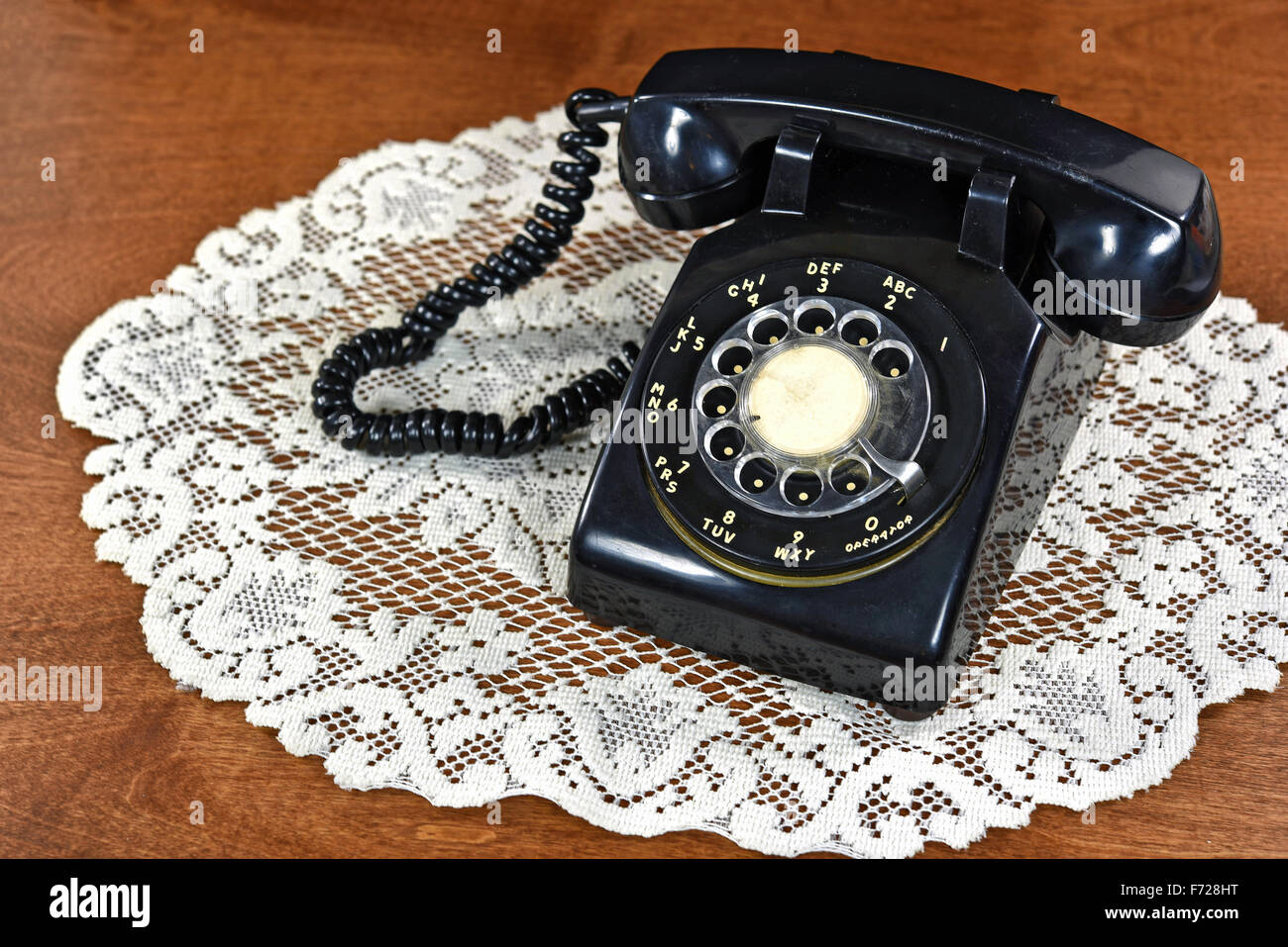 Schwarze retro Wählscheibe Telefon auf Spitzen-Deckchen. Stockfoto
