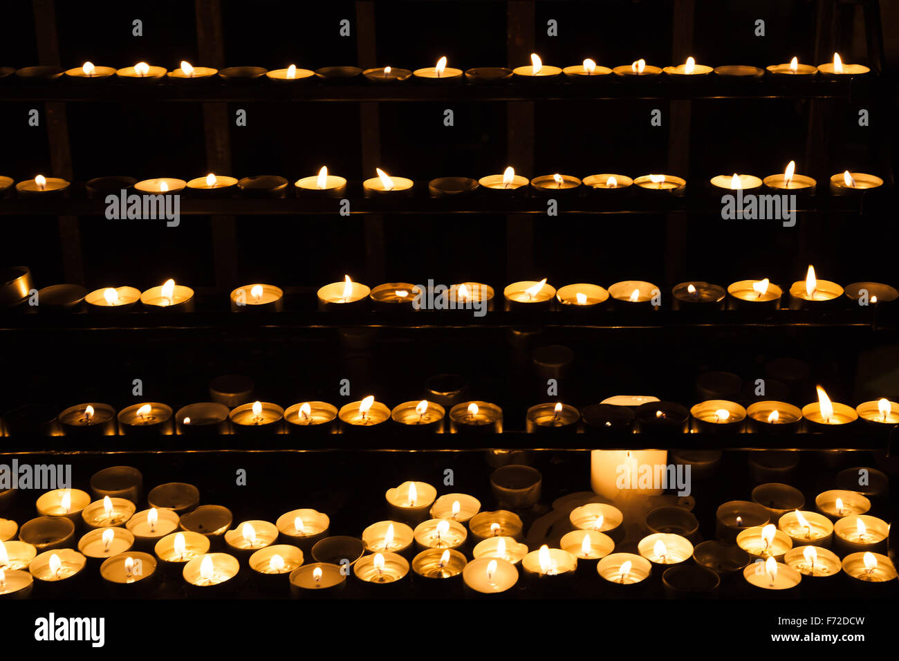 Kerzen brennen in den Regalen in dunklen katholische Kirche Stockfoto