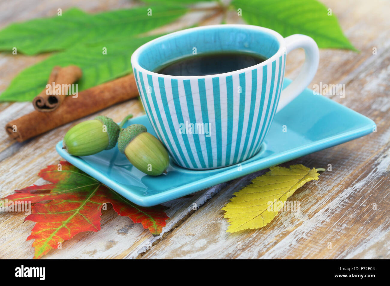 Tasse Kaffee, Herbstlaub und Eicheln auf rustikalen Holzoberfläche Stockfoto