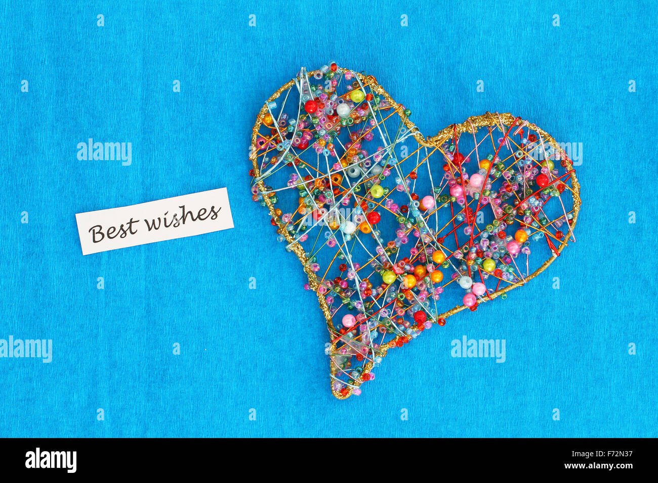 Die besten Wünsche Karte mit Herz gemacht von bunten Perlen auf blauem Hintergrund Stockfoto