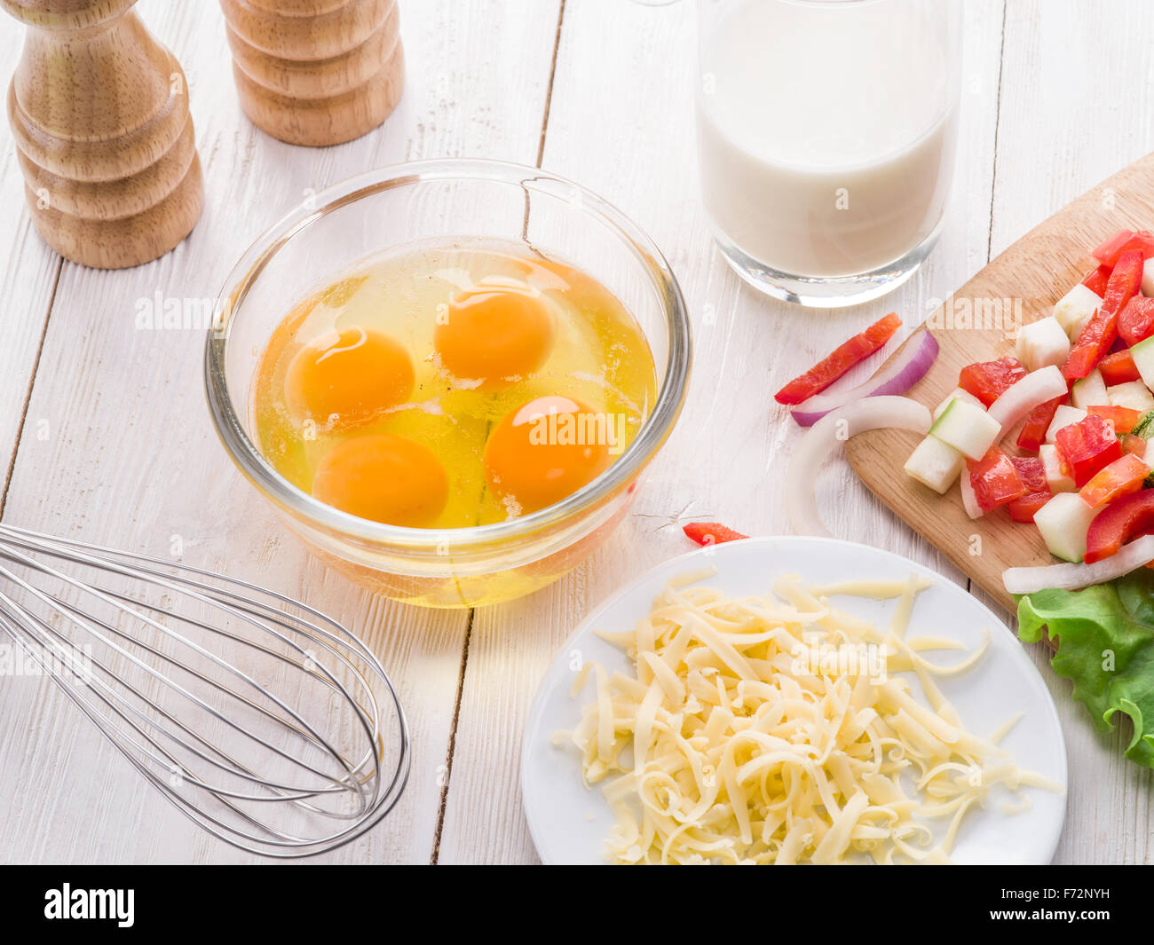 Omelette-Zutaten: Eiern, frisch geschnittene Gemüse, Milch und Käse auf dem Holztisch. Stockfoto