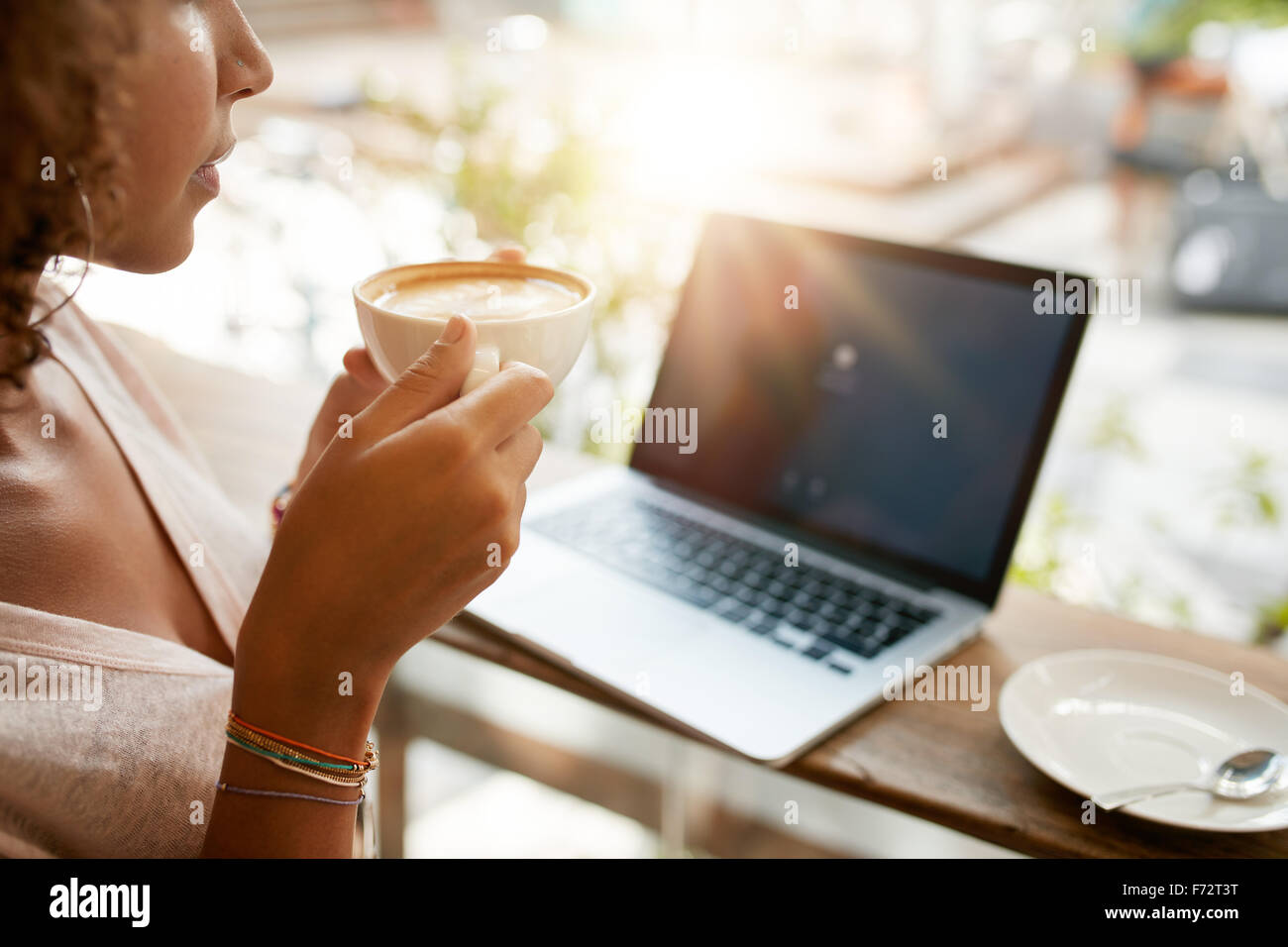 Bild der Frau Kaffee trinken mit einem Laptop am Tisch in einem Restaurant beschnitten. Junges Mädchen hält eine Tasse Kaffee im Café. Stockfoto