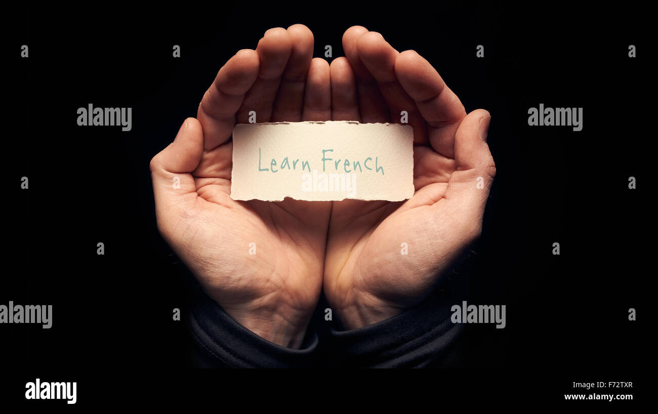 Ein Mann hält eine Karte in der hohlen Hand mit eine handschriftliche Nachricht drauf, Französisch lernen. Stockfoto