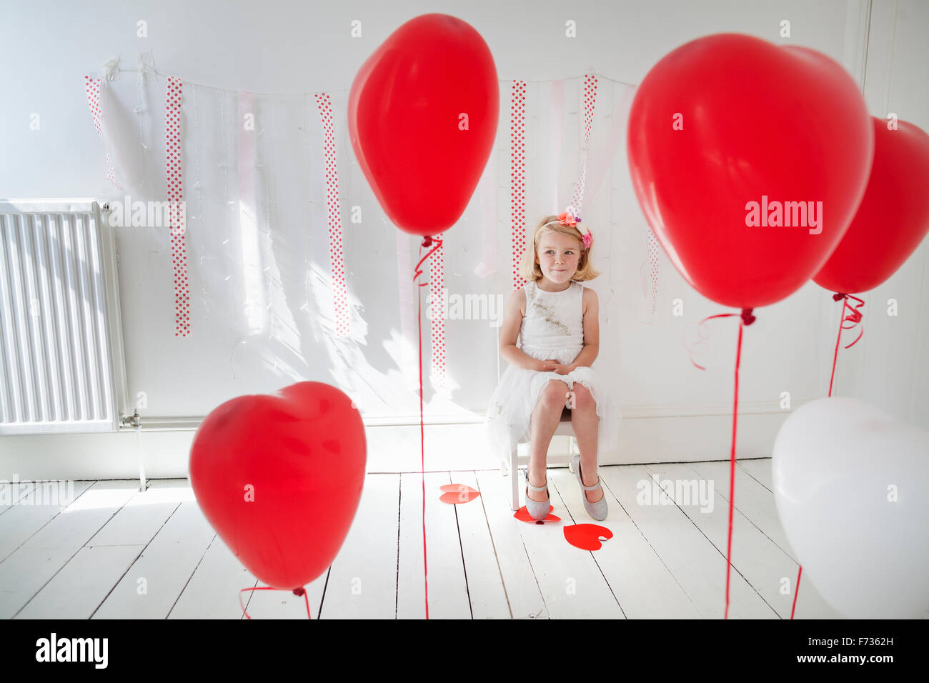 Junges Mädchen posieren für ein Foto in einem Fotografen Studio, umgeben von roten Luftballons. Stockfoto