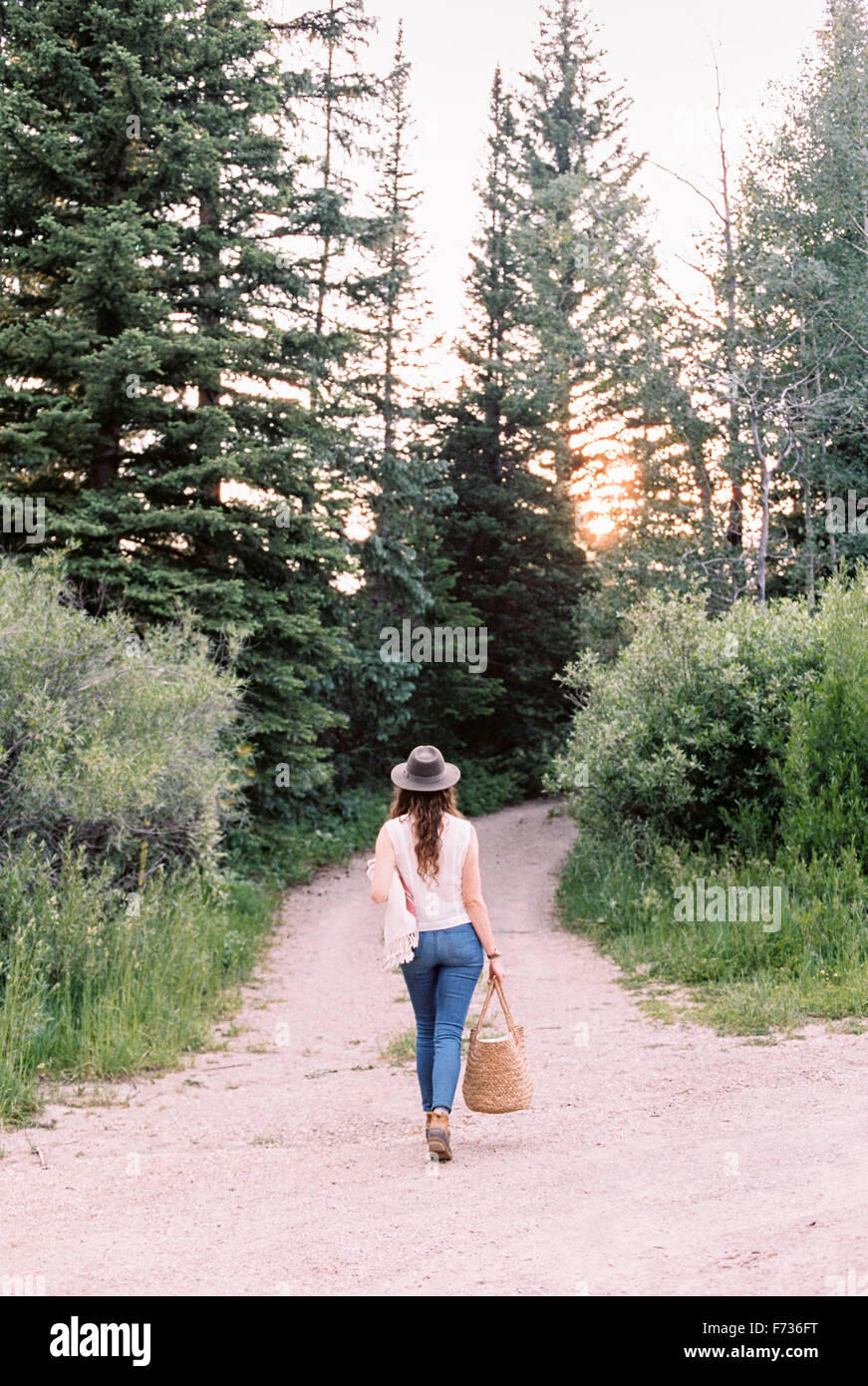 Frau zu Fuß über einen Waldweg mit einer Tasche. Stockfoto