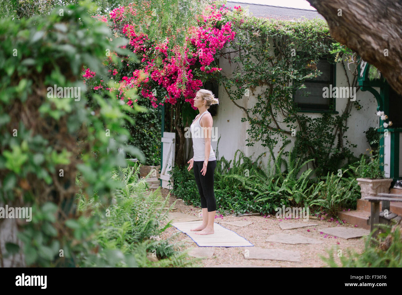 Blonde Frau, die Yoga in einem Garten zu tun. Stockfoto